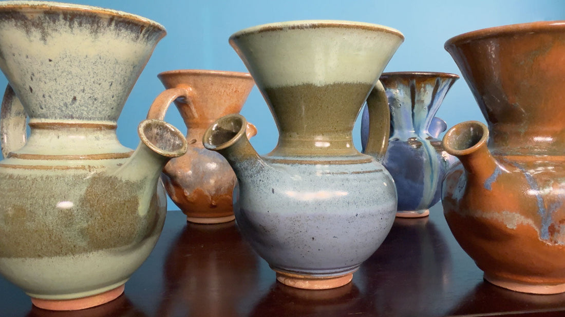 Handcrafted Costa Rican Vandola clay coffee brewers in various glazes displayed on a wooden table.