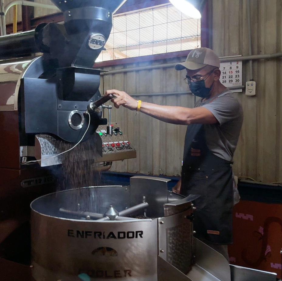 Person operating a coffee roasting machine in a workshop setting